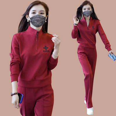 Sportisks divdaļīgs komplekts ar rāvējslēdzēja augšdaļu un izšuvumu un apakšā ar kabatu