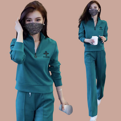 Sportisks divdaļīgs komplekts ar rāvējslēdzēja augšdaļu un izšuvumu un apakšā ar kabatu