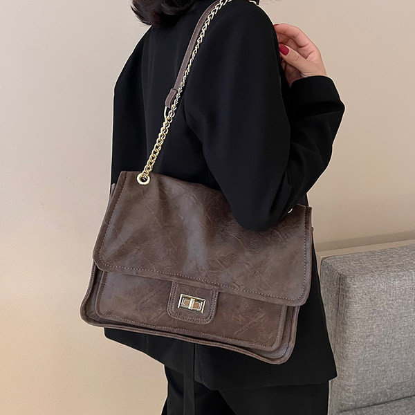 Kvadrātveida rokassomiņa ar ķēdes plecu rokturi un rāvējslēdzēja un sprādzes aizdari