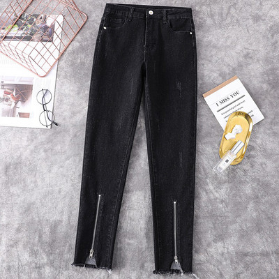 Kõrge vöökohaga naiste liibuvad teksad, mille säärtel on tõmblukk