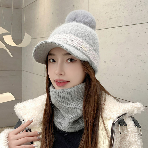 Moodne naiste müts visiiri ja pom-pomiga