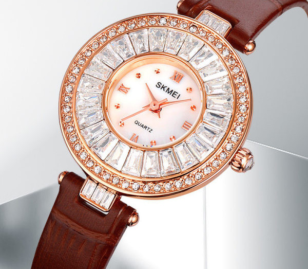 Ümara kuju ja kivikestega naiste käekell