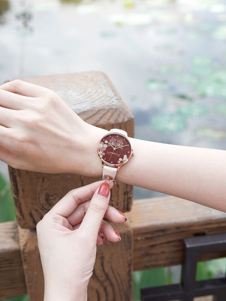 Dekoratiivsete elementide ja nahkrihmaga naiste käekell