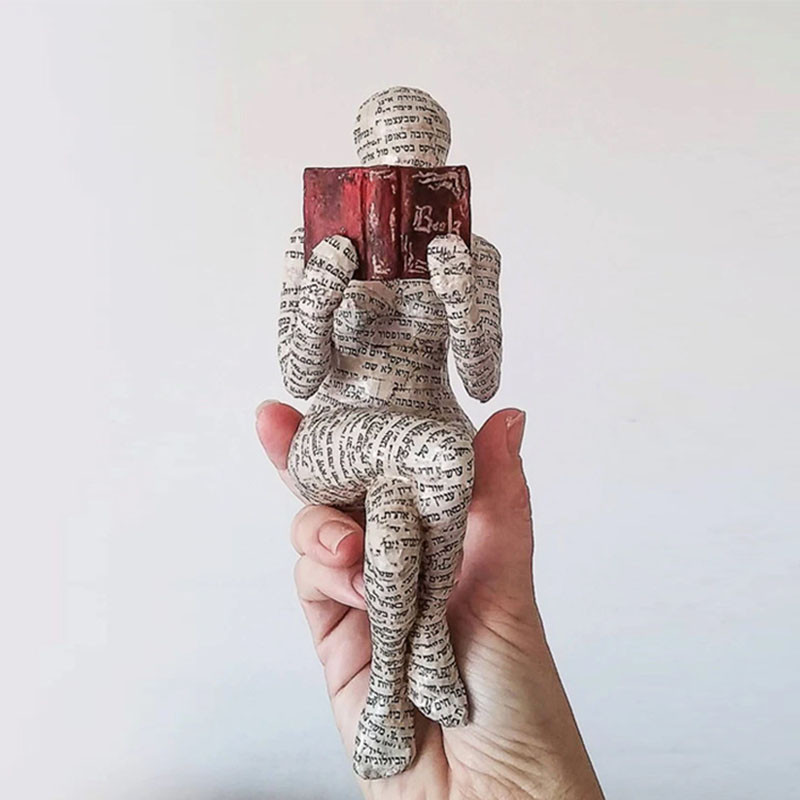 Moteris, kuri skaito popieriaus masės formeles, deda dirbinių dervą, deda gaminių knygų lentyną, kad papuoštų namų apyvokos reikmenis