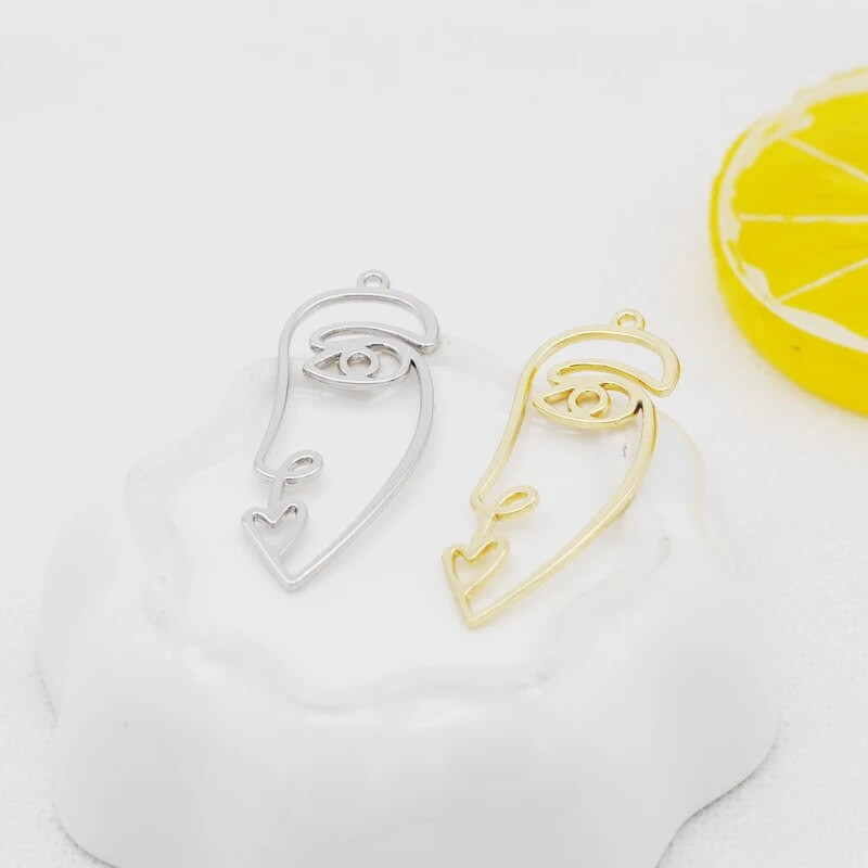 20 tk / partii uus saabumine kullavärvi õõnes abstraktne näo võlu ripatsid tsingi sulamist metallist amulettid ehete valmistamiseks 15 * 40 mm