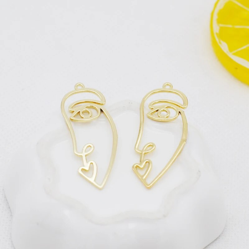 20 tk / partii uus saabumine kullavärvi õõnes abstraktne näo võlu ripatsid tsingi sulamist metallist amulettid ehete valmistamiseks 15 * 40 mm