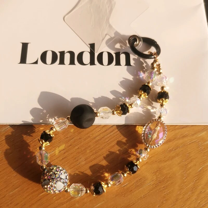 Mobilā tālruņa auklas īsa krāsaina dimanta dārgakmeņu plaukstas rokassprādze ar pilnu dimanta melna zelta kristāla pērlītēm pret zudumiem