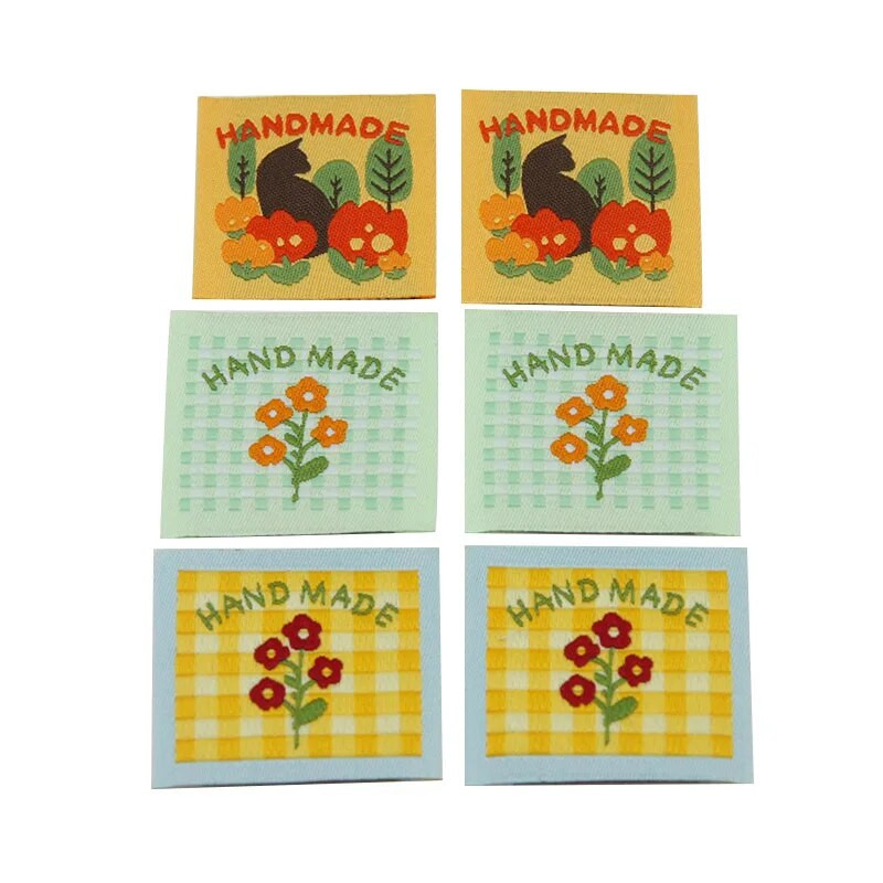 Ar rokām darināta auduma etiķete noliktavā, jauks pleds mazs zieds, kaķu izšuvumi, austa etiķete, aksesuāri, šūšana, krāsaina etiķete