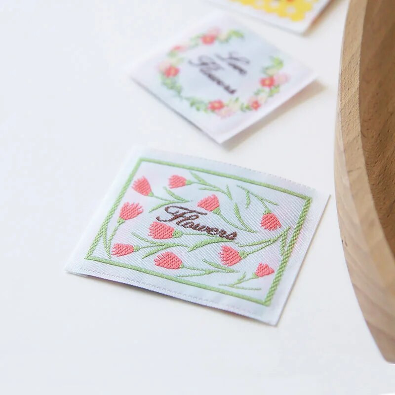 Jauna krāsaina roku darbs auduma etiķete ar sarežģītu ziedu sēriju, izšūtu austu etiķeti, palīgmateriāliem, šūšanas etiķeti