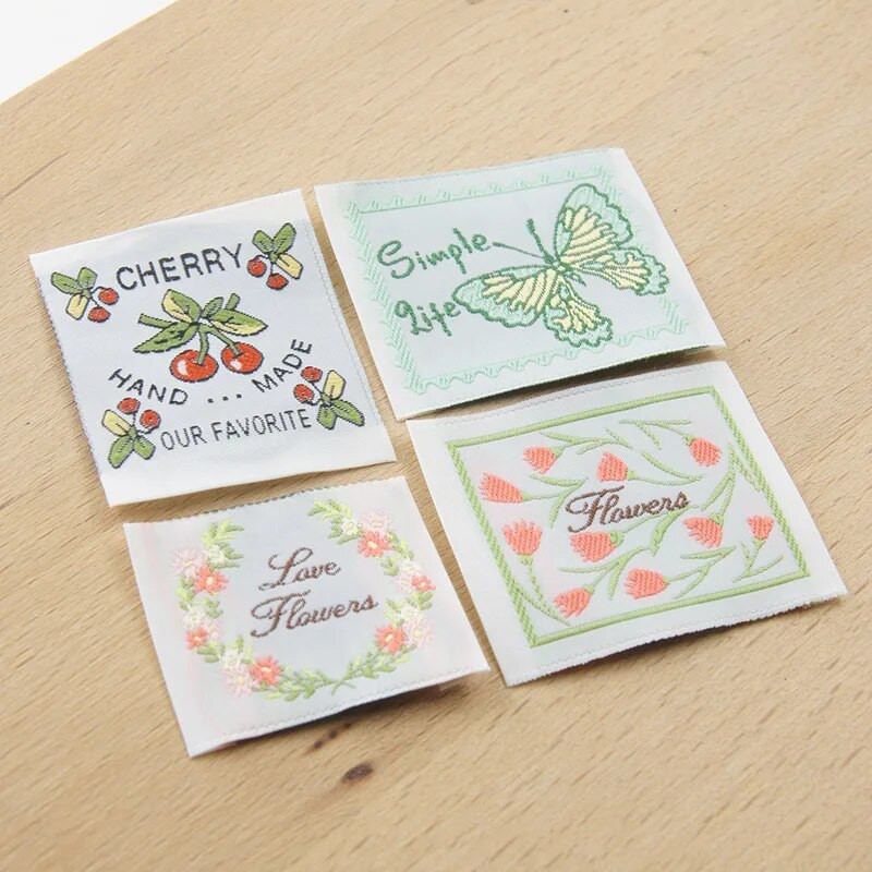 Jauna krāsaina roku darbs auduma etiķete ar sarežģītu ziedu sēriju, izšūtu austu etiķeti, palīgmateriāliem, šūšanas etiķeti