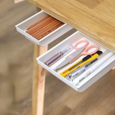 Isekleepuv pliiatsialus lauasahtli hoiukarbi all Peidetud kirjatarvete organiseerimisalus isekleepuva koduhoidiku jaoks